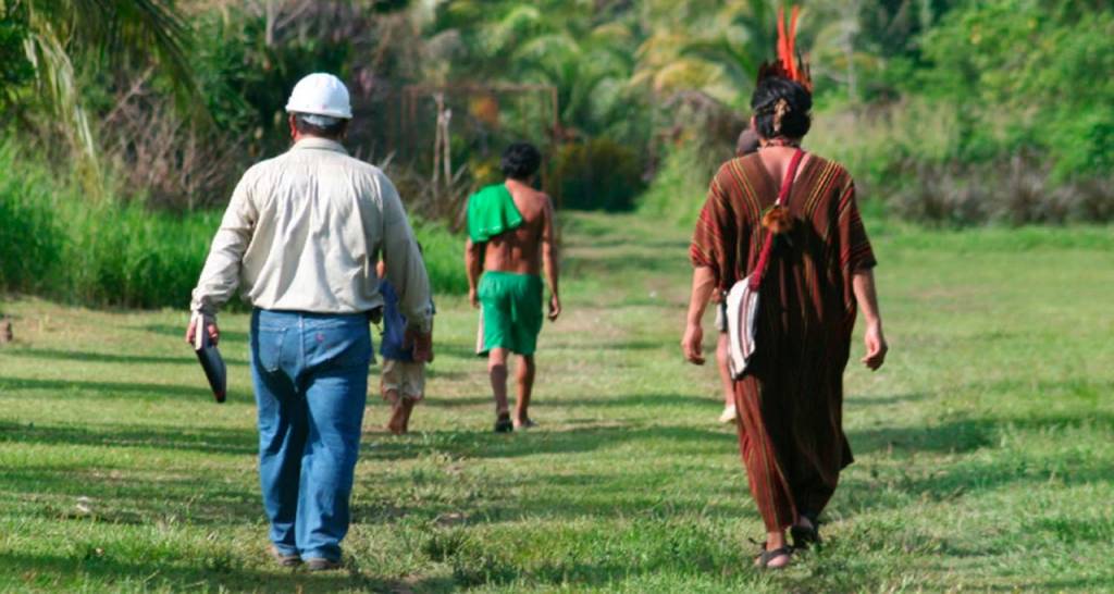 A Repsol employee walks with an indigenous community member.