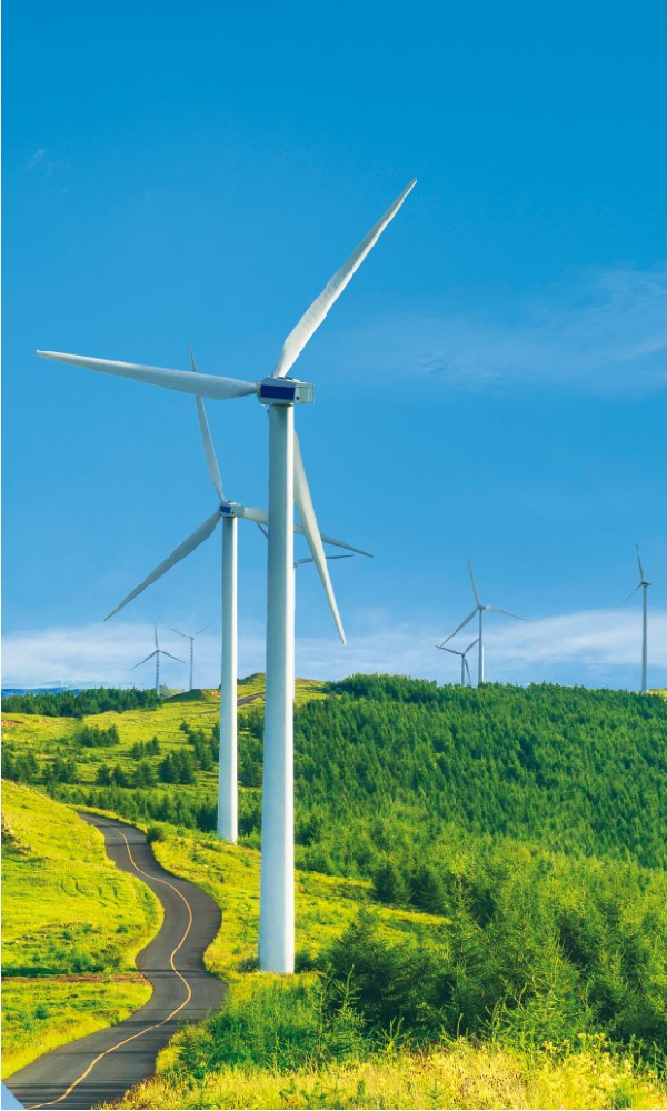 Wind turbines next to a road running through a field